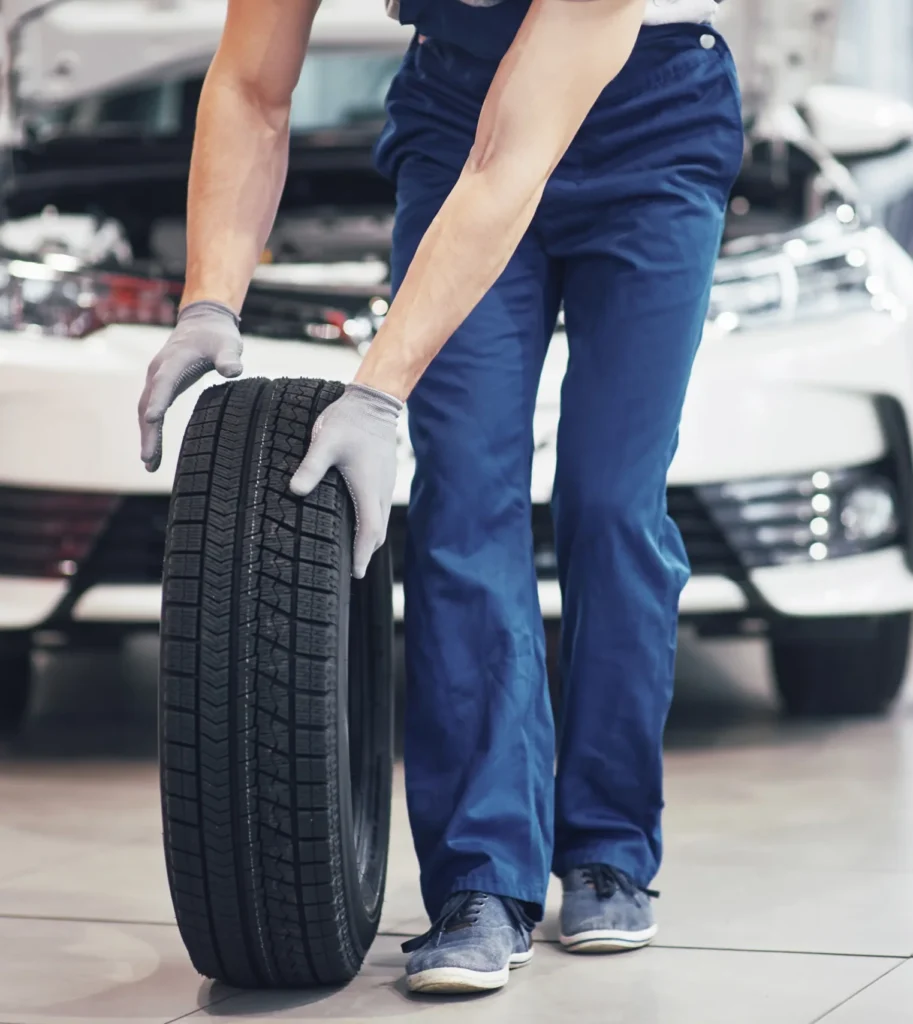 mecanico sosteniendo un neumatico en el garaje de reparacion reemplazo de neumaticos de invierno y verano